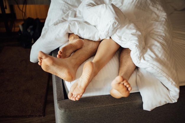 Los pies de una joven pareja heterosexual relajándose en la cama.