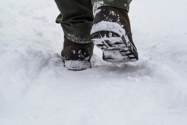 Pies masculinos con botas caminando en la nieve del invierno