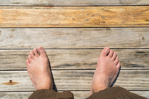 Foto los pies masculinos de pie en el piso de madera vista superior espacio de copia para el texto