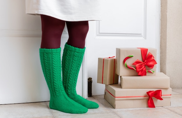 Pies de mujer en calcetines verdes parados cerca de regalos