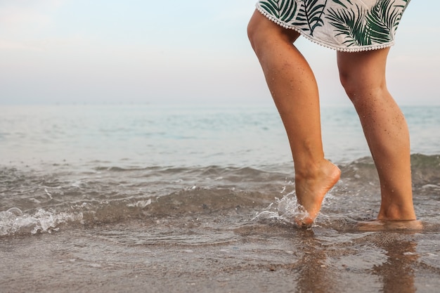 Foto los pies de la mujer caminan lentamente y se relajan en la arena de la playa tropical con fondo de cielo azul. concepto de vacaciones y vacaciones.