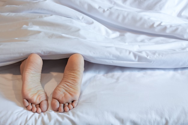 Pies de mujer dormida en la cama blanca