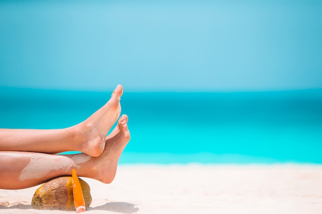 Pies de mujer en la playa de arena blanca en aguas poco profundas