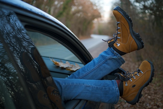 Pies de mujer en la puerta del coche Pies fuera de la ventana en el bosque al atardecer