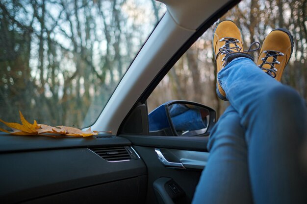 Pies de mujer en la puerta del coche Pies fuera de la ventana en el bosque al atardecer