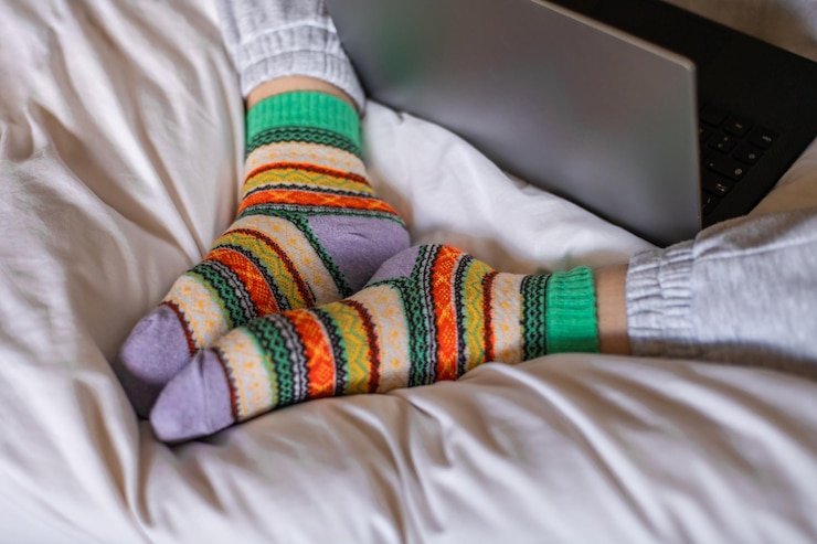 Foto los pies de las mujeres en calcetines de colores cálidos en una cama de cerca