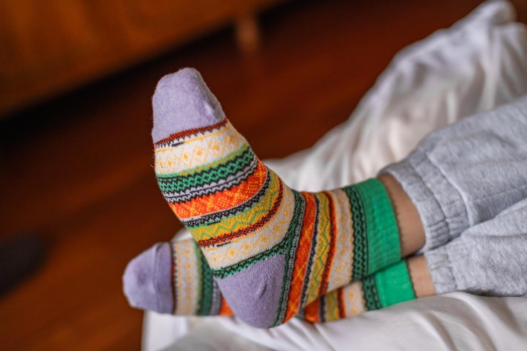 Foto los pies de las mujeres en calcetines de colores cálidos en una cama de cerca