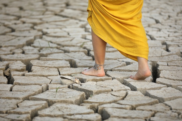 Los pies de las mujeres caminan sobre la tierra seca.