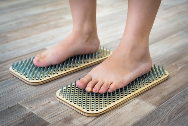 Los pies de las mujeres están de pie sobre una tabla con clavos afilados, Tablero Sadhu. práctica de yoga. dolor, prueba, salud.