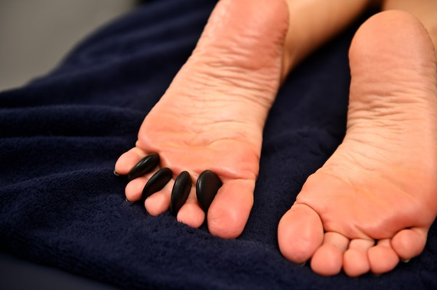 Los pies de las mujeres se masajean con piedras calientes conceptos de spa.