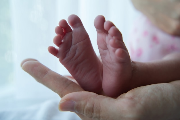 Pies de niña en la mano de su madre.