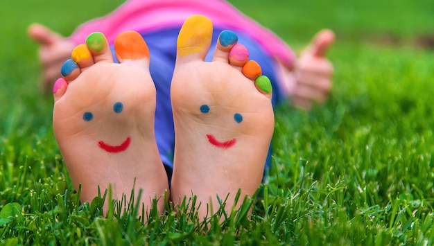 Pies de un niño en la hierba con una sonrisa pintada Foco de selección