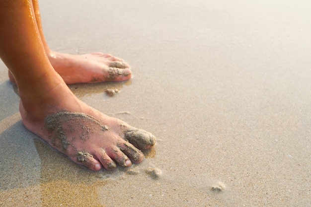 Pies de un niño en la playa de arena