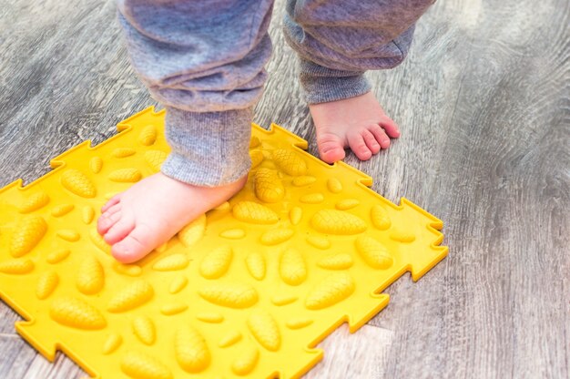 Los pies del niño en el primer plano de la estera ortopédica.