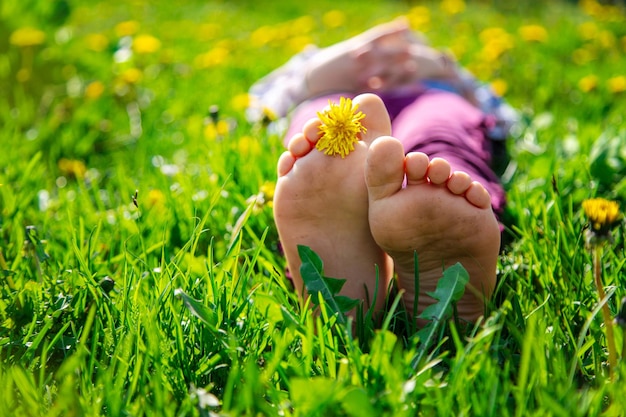 Pies de niño sobre la hierba en el jardín de dientes de león de primavera Enfoque selectivo