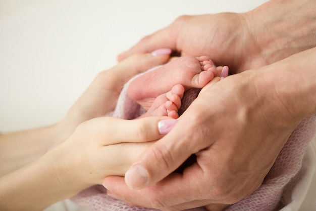 Pies de los niños en manos de la madre y el padre. Madre, padre e hijo. Concepto de personas de familia feliz. Foto de alta calidad