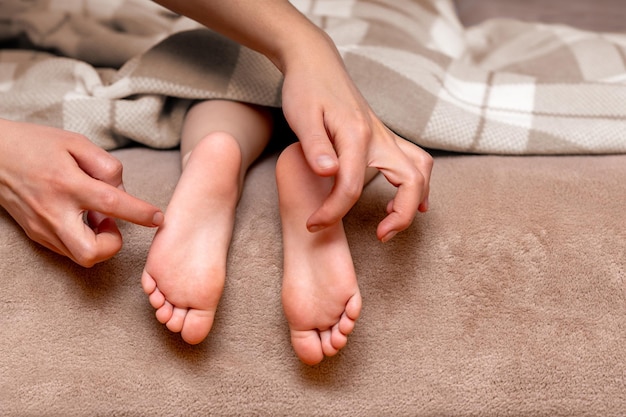 Los pies de los niños bajo una manta son cosquilleados por la mano de sus madres