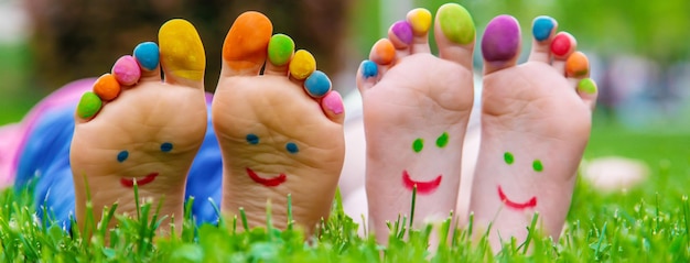 Los pies de los niños con un patrón de pinturas sonríen en la hierba verde Enfoque selectivo