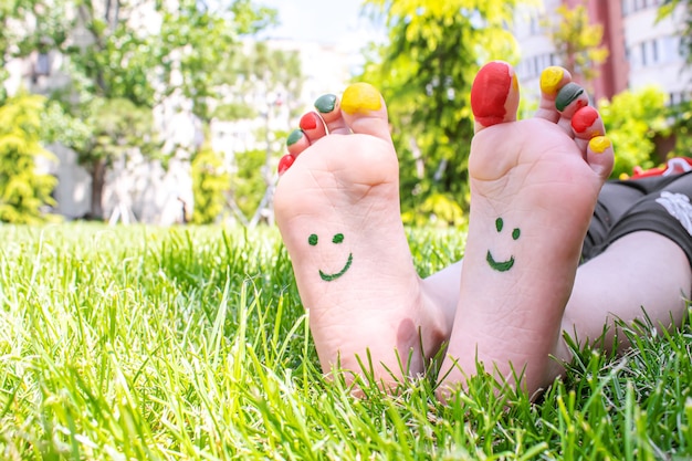 Los pies de los niños con un patrón de pinturas sonríen sobre la hierba verde. Enfoque selectivo. naturaleza.