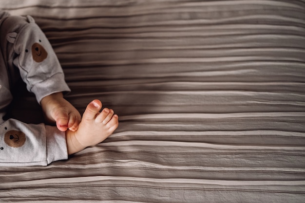 Los pies de los niños sobre telas a rayas emergen como una elegante manta marrón