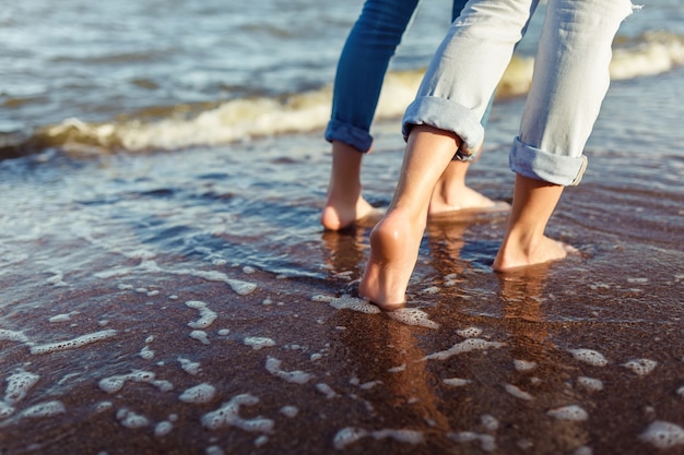 Pies de pareja mujer y hombre en las olas del mar