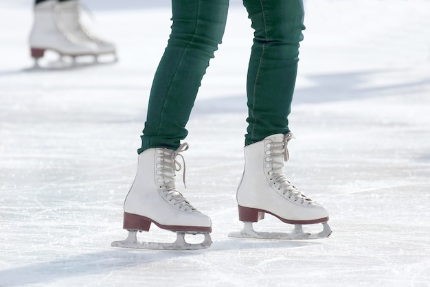 Pies patinaje niña patinando en pista de hielo. Deporte y entretenimiento. Descanso y vacaciones de invierno.