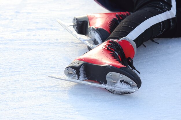 Pies en patines de un hombre caído en una pista de hielo