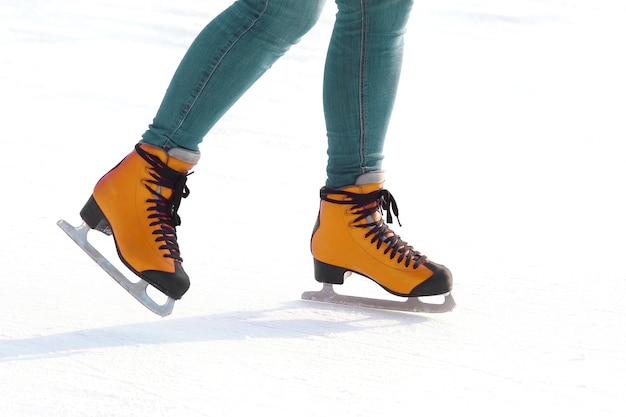 Pies en patines en una pista de hielo. deportes, pasatiempos y recreación de personas activas