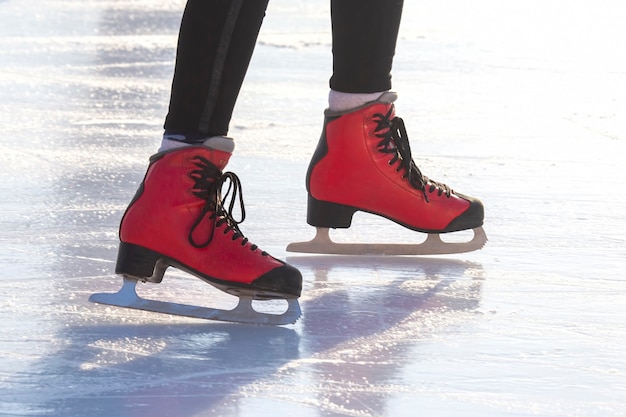 Pies en patines rojos sobre una pista de hielo. aficiones y ocio. Deportes de invierno