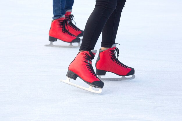 Pies en patines rojos sobre una pista de hielo. Pasatiempos y deportes. Vacaciones y actividades invernales.