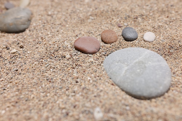 Los pies pequeños están hechos de piedras sobre la estufa en la playa de mar closeup