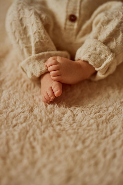 Pies de un recién nacido el bebé está vestido con un cálido traje de punto