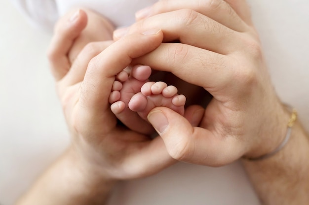 Pies de un recién nacido en manos de un padre, padre. Fotografía de estudio, fondo blanco. Concepto de familia feliz. Foto de alta calidad