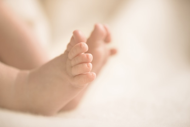 Foto pies recién nacidos del bebé en la manta cremosa. mamá y su hijo. maternidad, familia, concepto de nacimiento.