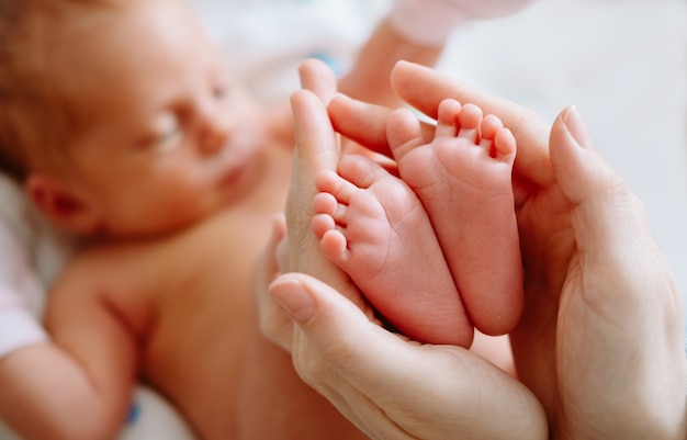 Pies recién nacidos lindos en manos de la madre. Concepto de familia feliz.