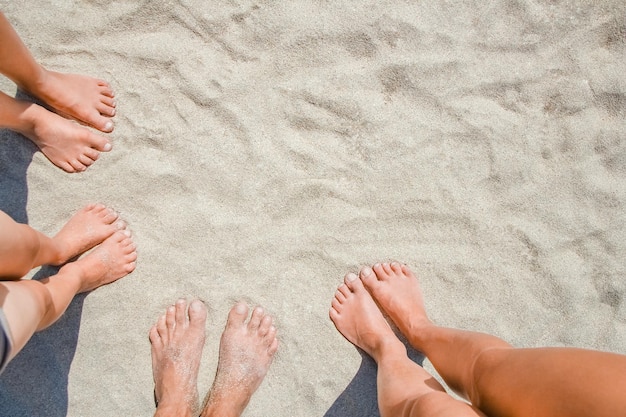 Unos pies sobre la arena de gente feliz junto al mar en viajes por la naturaleza