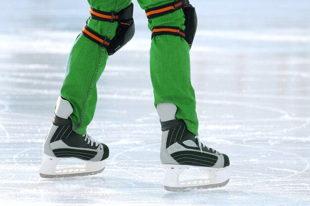 Pies sobre los patines de una persona que rueda sobre la pista de hielo. deportes de vacaciones y pasatiempos