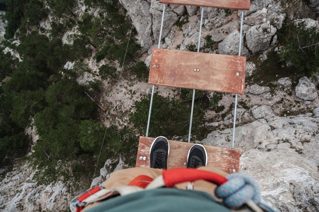 Pies de turista masculino cruzando un abismo en las montañas en un puente colgante