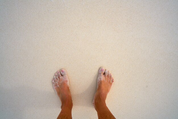 Pies de turista en playa tropical de arena blanca