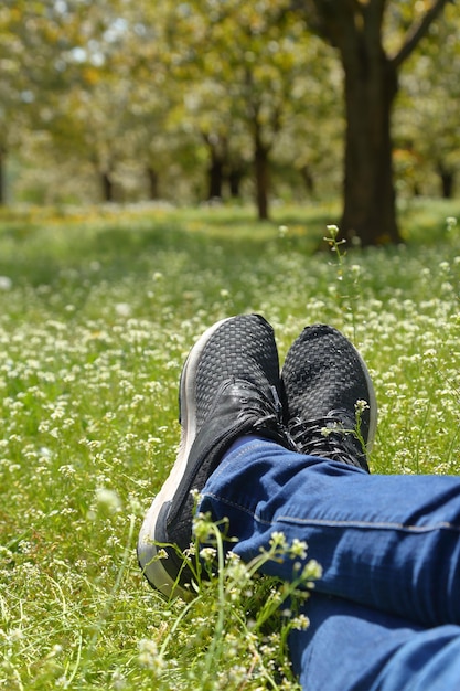 Pies en zapatos en campo verde con flores.