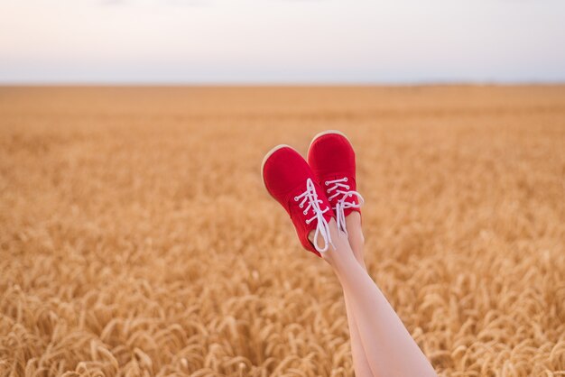 Pies en zapatos rojos graciosos que sobresalen del campo de trigo. ser uno mismo.