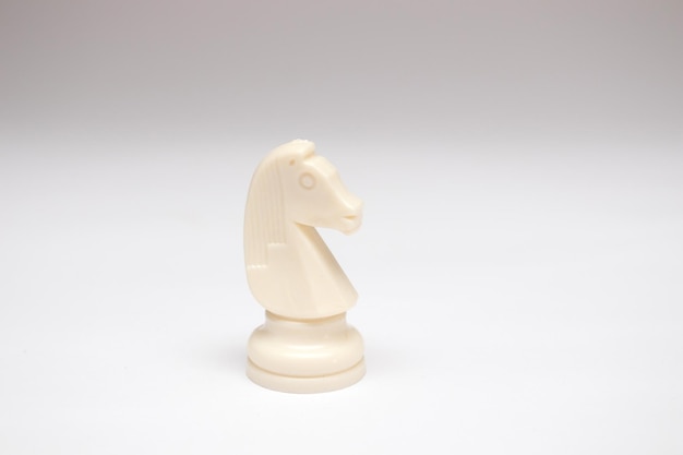 Pieza de ajedrez caballo blanco sobre fondo blanco.