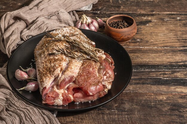 Pieza de carne de pavo cruda marinada con especias. Un ingrediente útil para preparar alimentos saludables. Una luz dura moderna, sombra oscura, estilo rústico. Mesa de madera vintage, espacio de copia