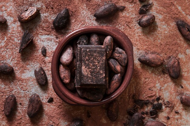 Pieza de chocolate y granos de cacao en el tazón