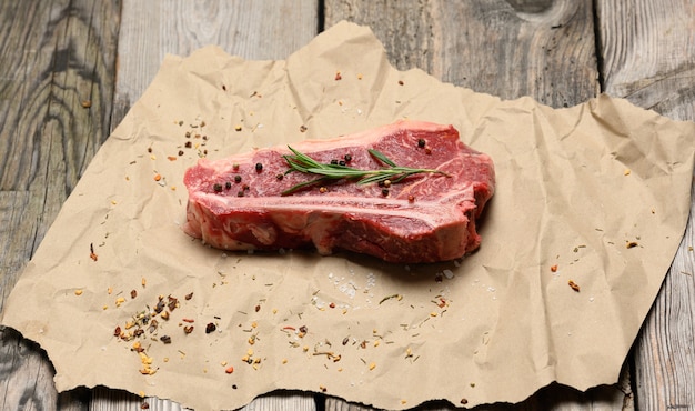 Pieza cruda fresca de carne de vacuno, bistec de lomo sobre una superficie de papel, vista superior. Pedazo de carne veteada Nueva York