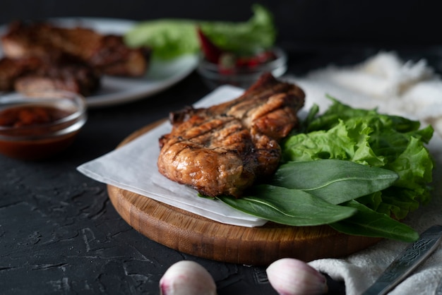 Pieza de filete de cerdo asado cocido con hojas de lechuga, cebolla y salsa, carnes chatarra