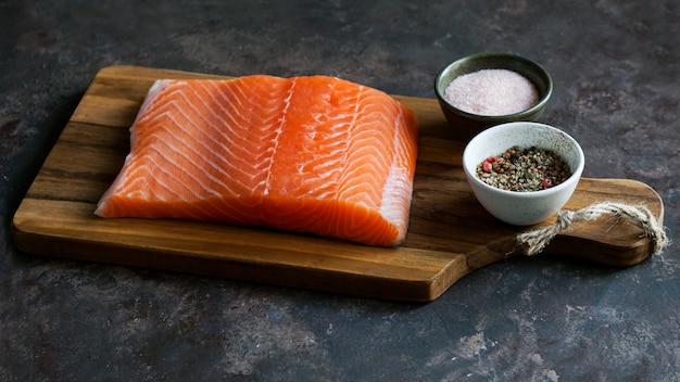 Pieza fresca cruda de salmón en la tabla de cortar