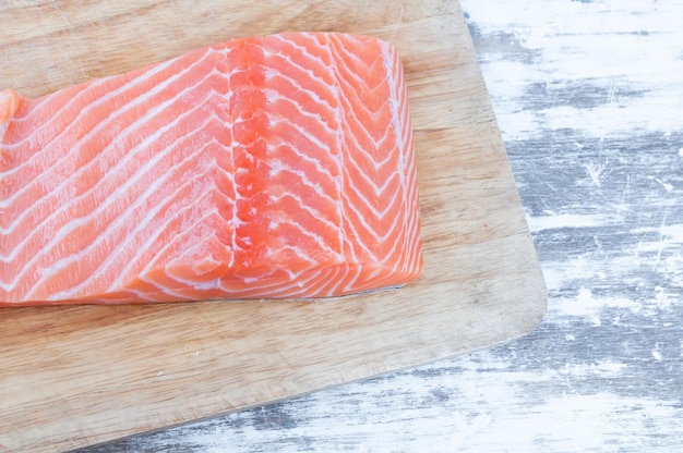 Foto pieza de pescado de salmón crudo crudo fresco sobre fondo de tablero de madera