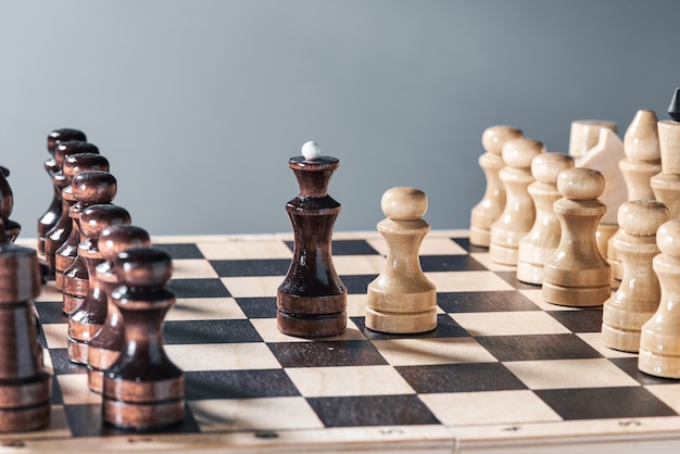 Foto piezas de ajedrez de madera en un tablero de ajedrez, el enfrentamiento del peón blanco y la reina negra, concepto de planificación y toma de decisiones