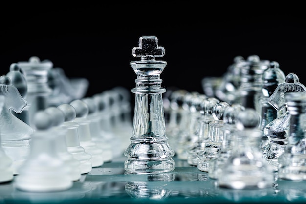 Piezas de ajedrez de vidrio transparente sobre fondo oscuro Enfoque selectivo del concepto de liderazgo y estrategia